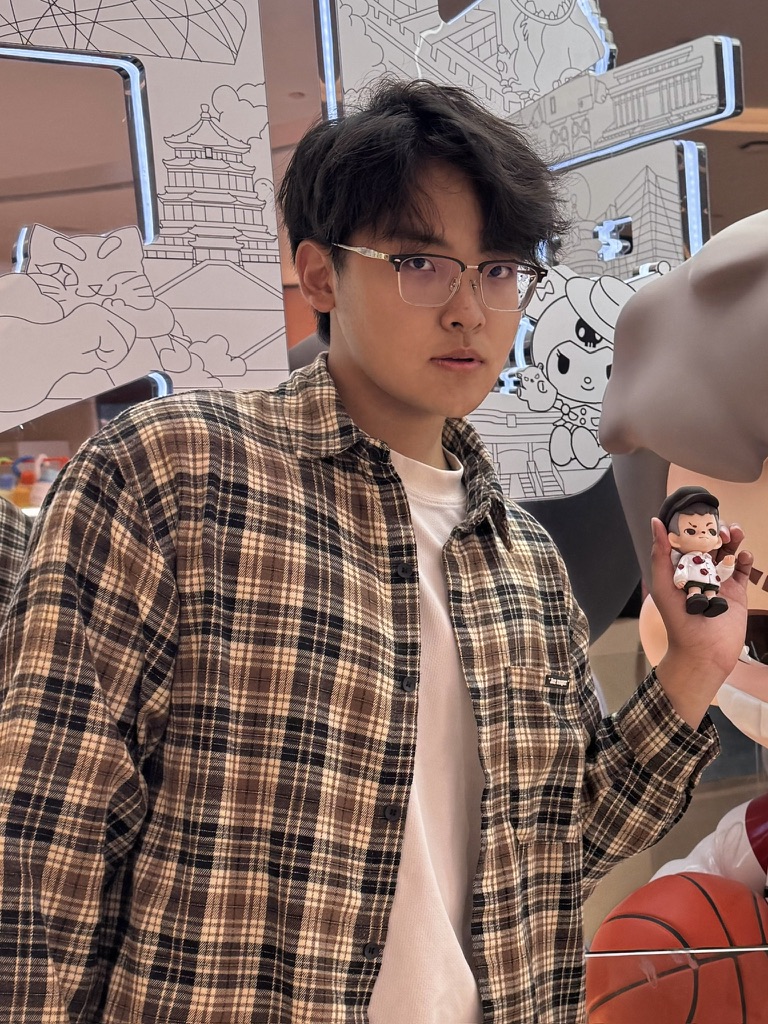 Changjian Liu holding a small figurine in front of illustrated Beijing landmarks